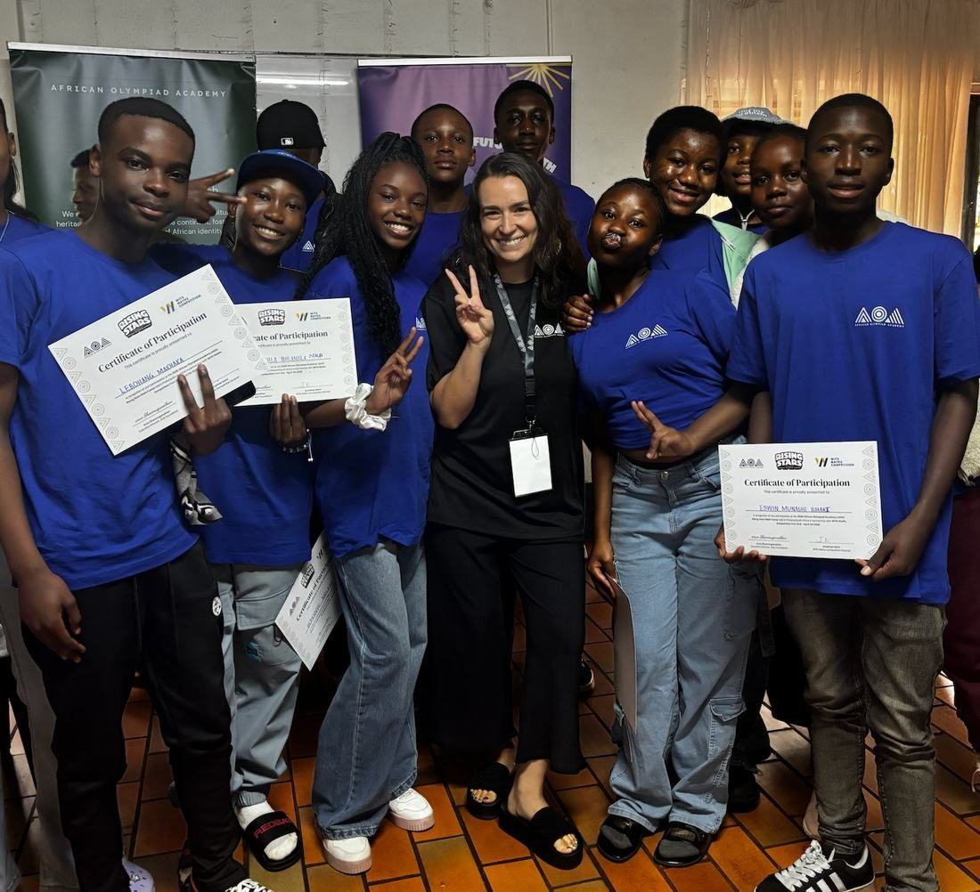 Fifty-six smiling students holding certificates at the Rising Stars Math Camp closing ceremony