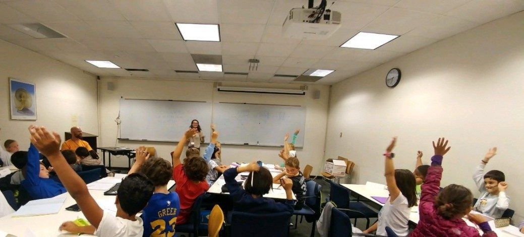 Students eagerly raising their hands during a Berkeley Math Circle class